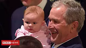 George W Bush cuddles baby during visit to father's casket