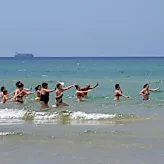 Οι beachgoers χορεύουν στην Ιταλία, καθώς το πλοίο που μεταφέρει τους μετανάστες στέκεται ανοικτά, περιμένοντας ένα λιμάνι